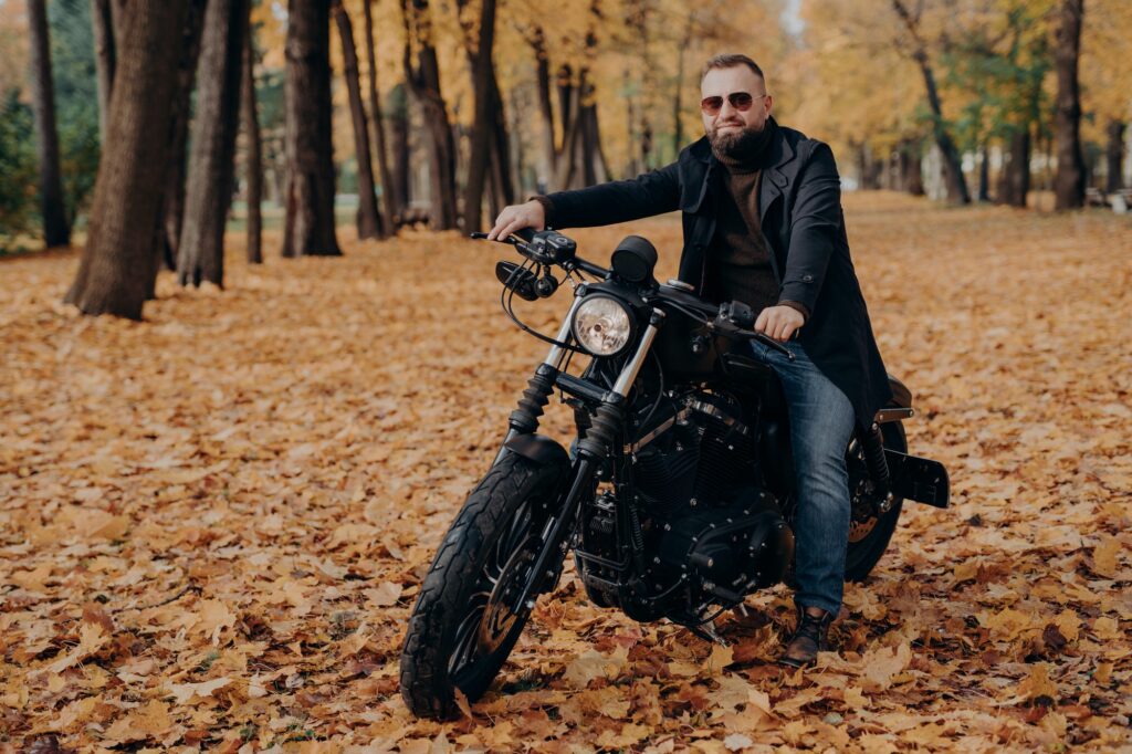 fashionable-male-motorcycle-driver-poses-on-black-motorbike-rides-in-beautiful-yellow-park.jpg